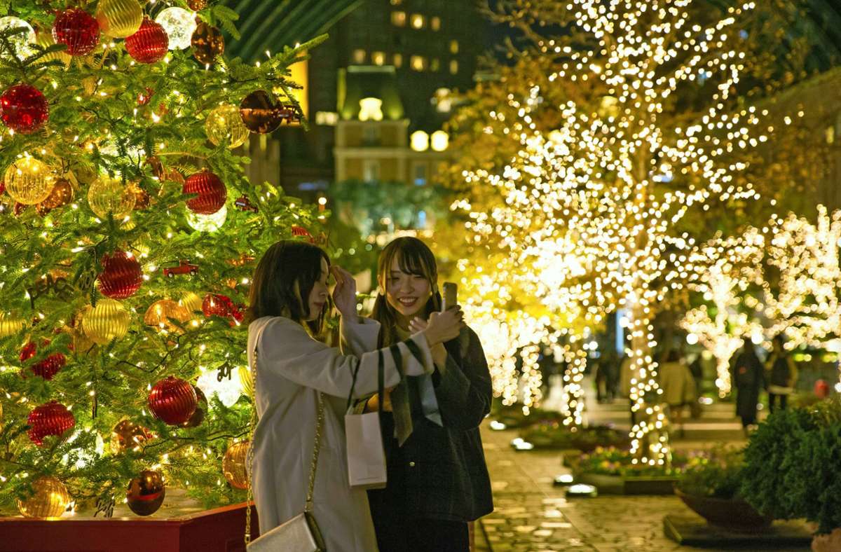 Zwei Japanerinnen machen Selfies vor einem Weihnachtsbaum in Tokio. Foto: imago/ZUMA Wire