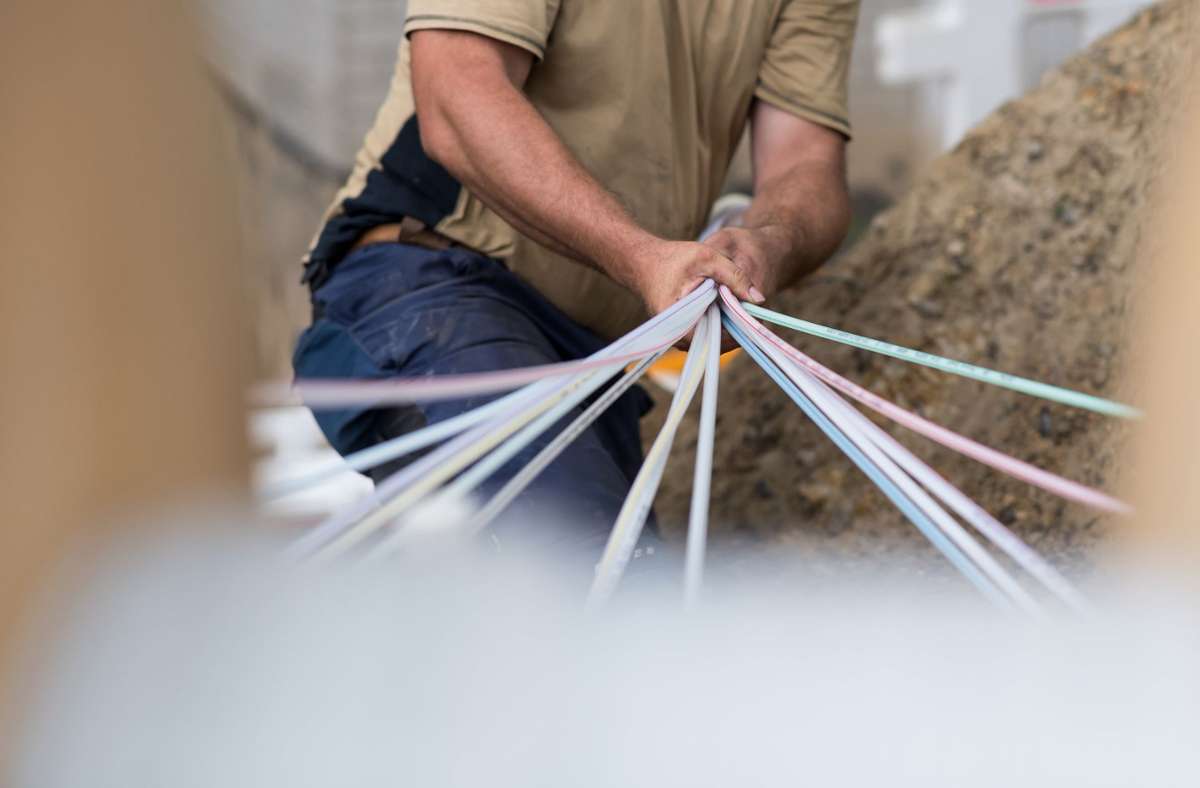 Ein Bauarbeiter hält ein Bündel Leerrohre in der Hand, durch die Glasfaserkabel gezogen werden sollen. Foto: dpa/Guido Kirchner