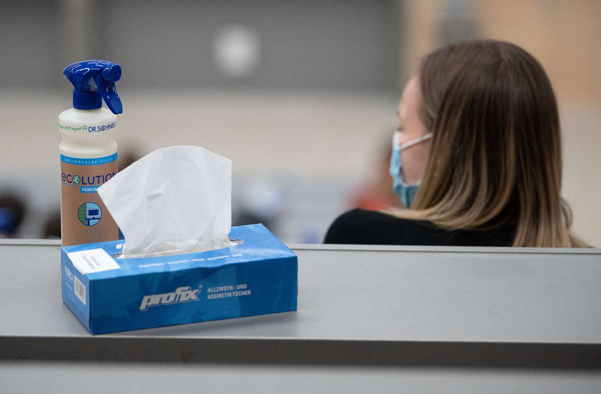 Eine Box mit Papiertüchern und eine Sprühflasche mit Desinfektionsmittel steht neben einer Studentin  der Universität Hohenheim. Foto: dpa/Sebastian Gollnow