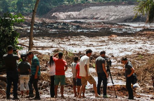 Menschen beobachten die Schlammmassen nach dem Bruch eines Staudamms an der Feijão Eisenerzmine in Brasilien. Foto: dpa/Rodney Costa