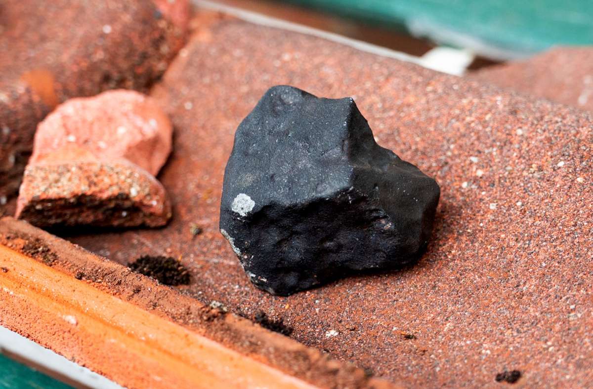 April 2023: Ein kleiner schwarzer Meteorit liegt auf einer zerbrochenen Dachpfanne. Der Gesteinsbrocken von der Größe eines Tennisballs hatte das Dach eines Hauses durchschlagen.