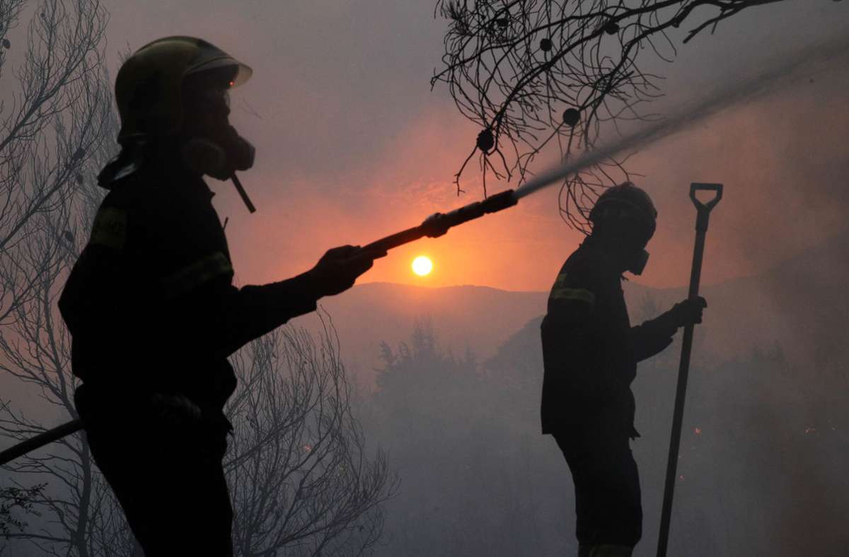 Feuerwehrleute kämpfen gegen den Waldbrand, der am Dienstag auf Vororte von Athen übergegriffen hat. Foto: dpa/Marios Lolos