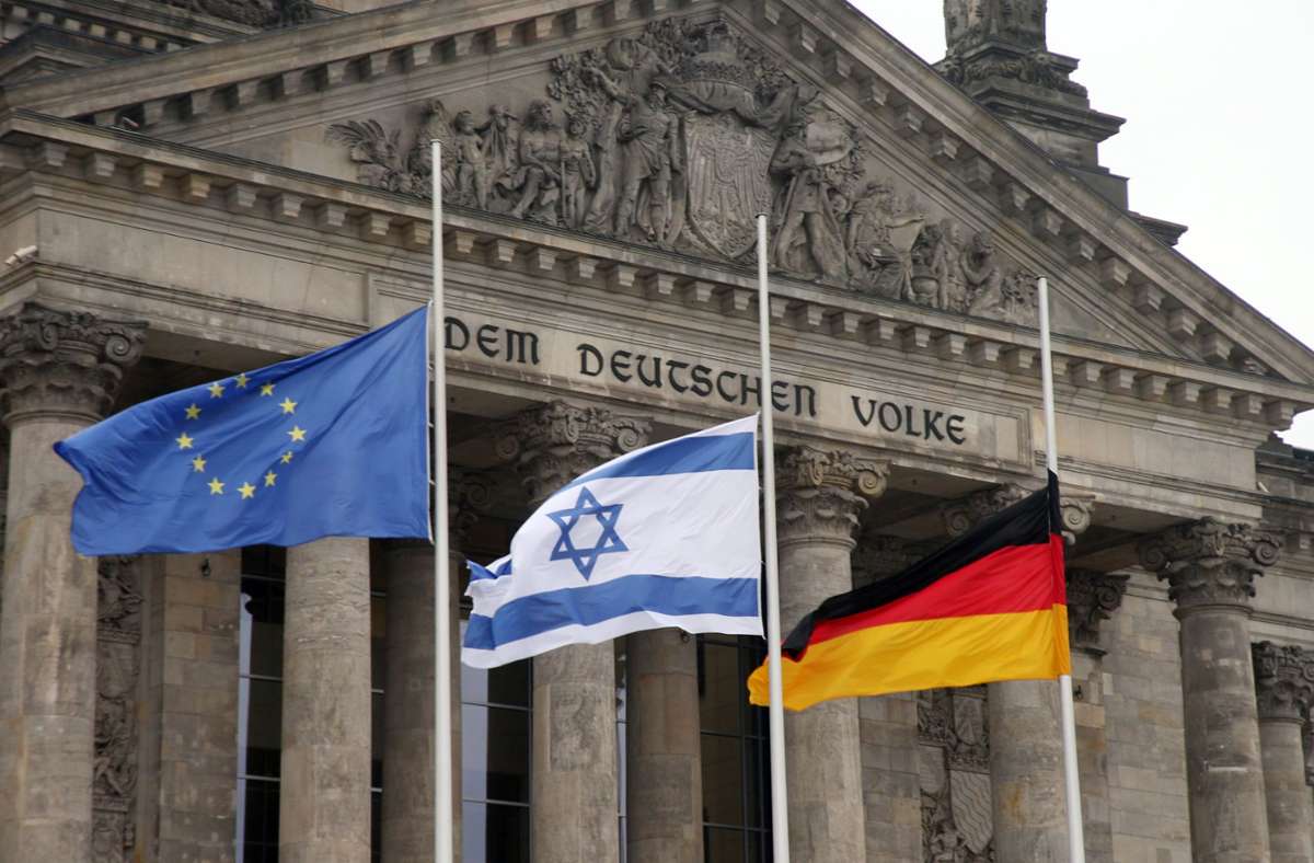 Die europäische, die israelische und die deutsche Flagge auf halbmast vor dem Reichstag in Berlin. Foto: dpa/Wolfgang Kumm