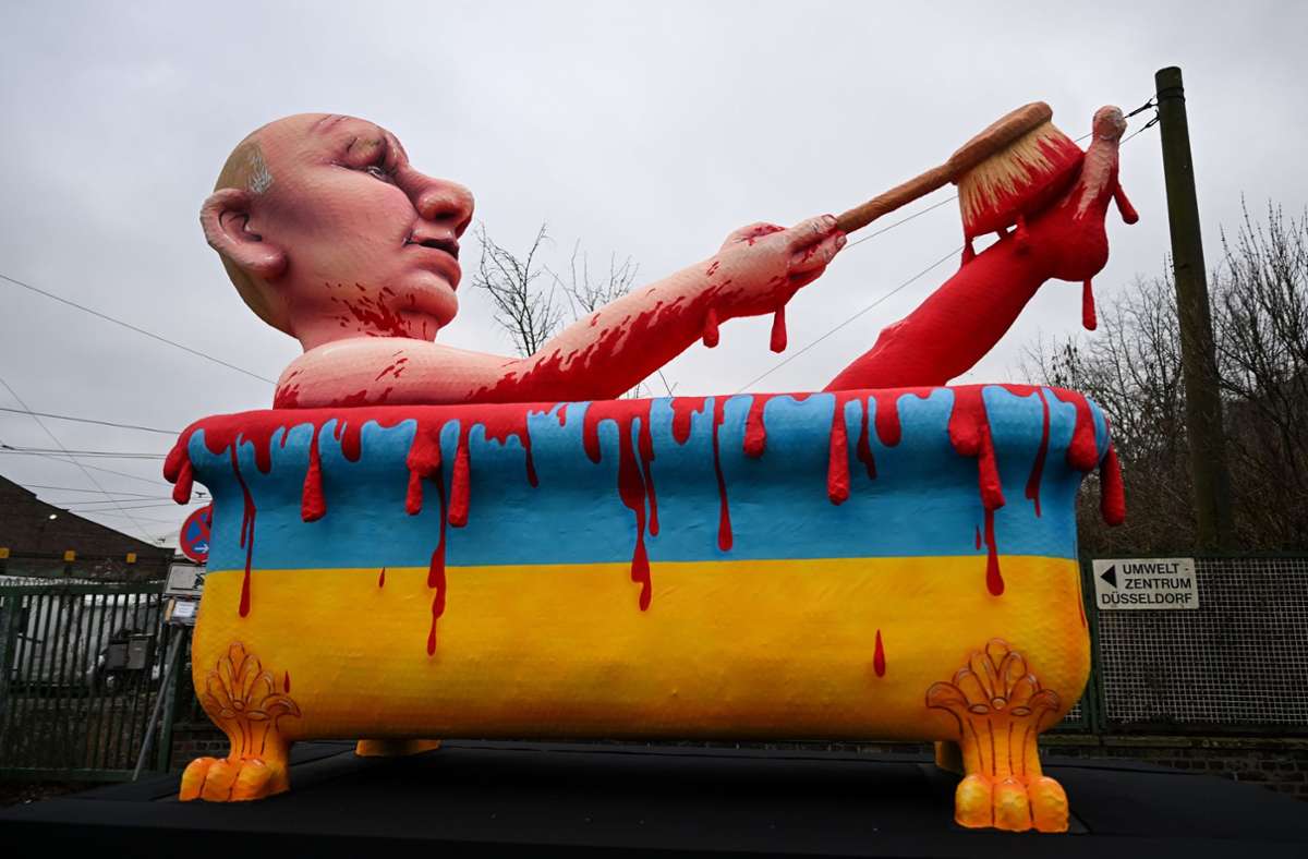 Wladimir Putin nimmt ein Blutbad – in einer Badewanne in den ukrainischen Landesfarben. Ein Umzugswagen steht für den Rosenmontagsumzug in Düsseldorf bereit.