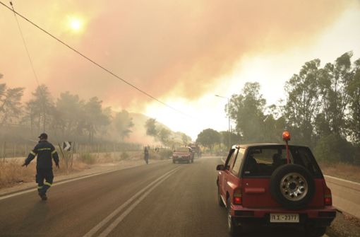 Feuerwehrleute bekämpfen einen Waldbrand in der Nähe des Dorfes Lampiri, gefährlich nah zu den Küstenstädten. Foto: AP/dpa/Andreas Alexopoulos