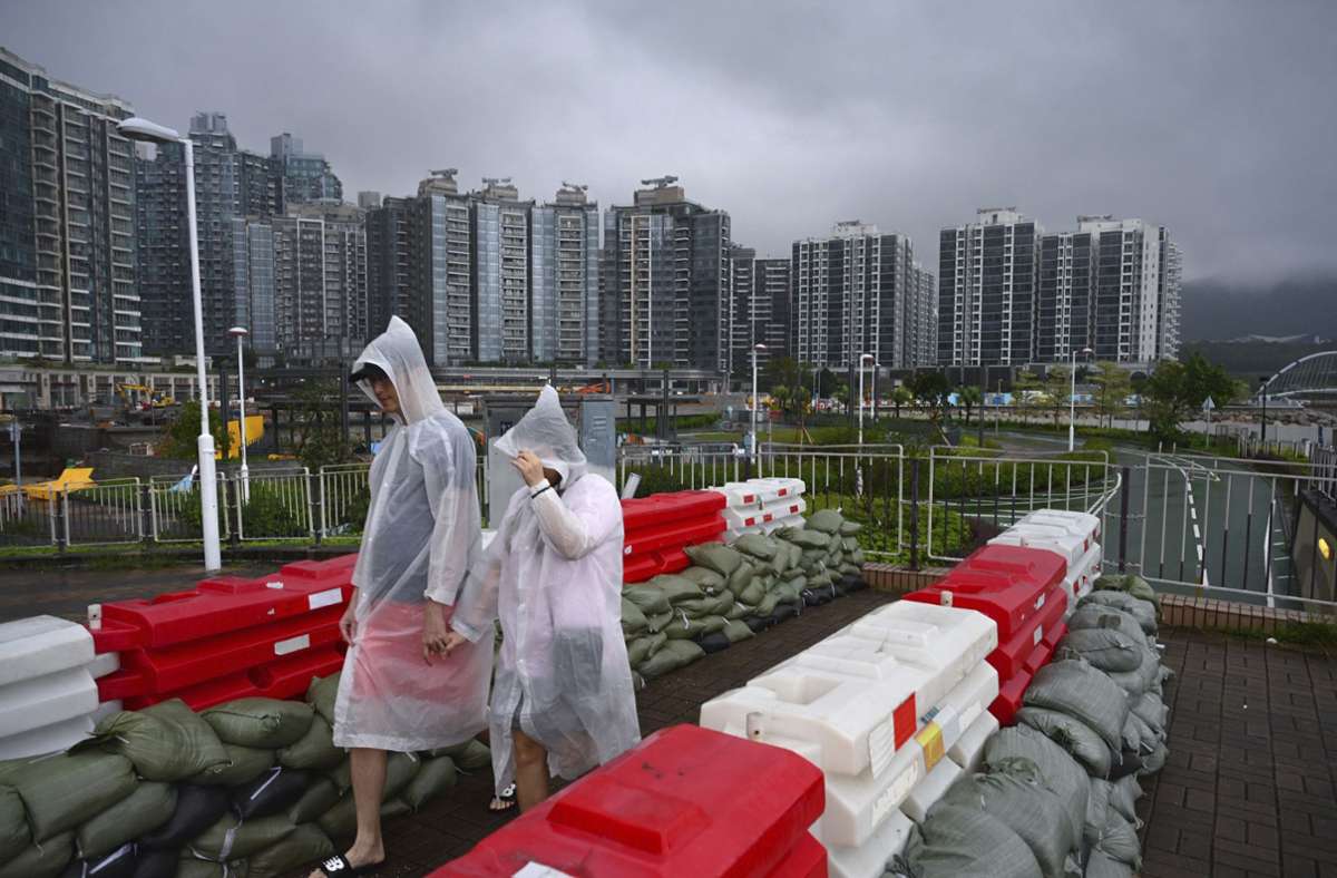 Menschen in Regenmänteln gehen in Hongkong  an Sandsackbarrikaden vorbei