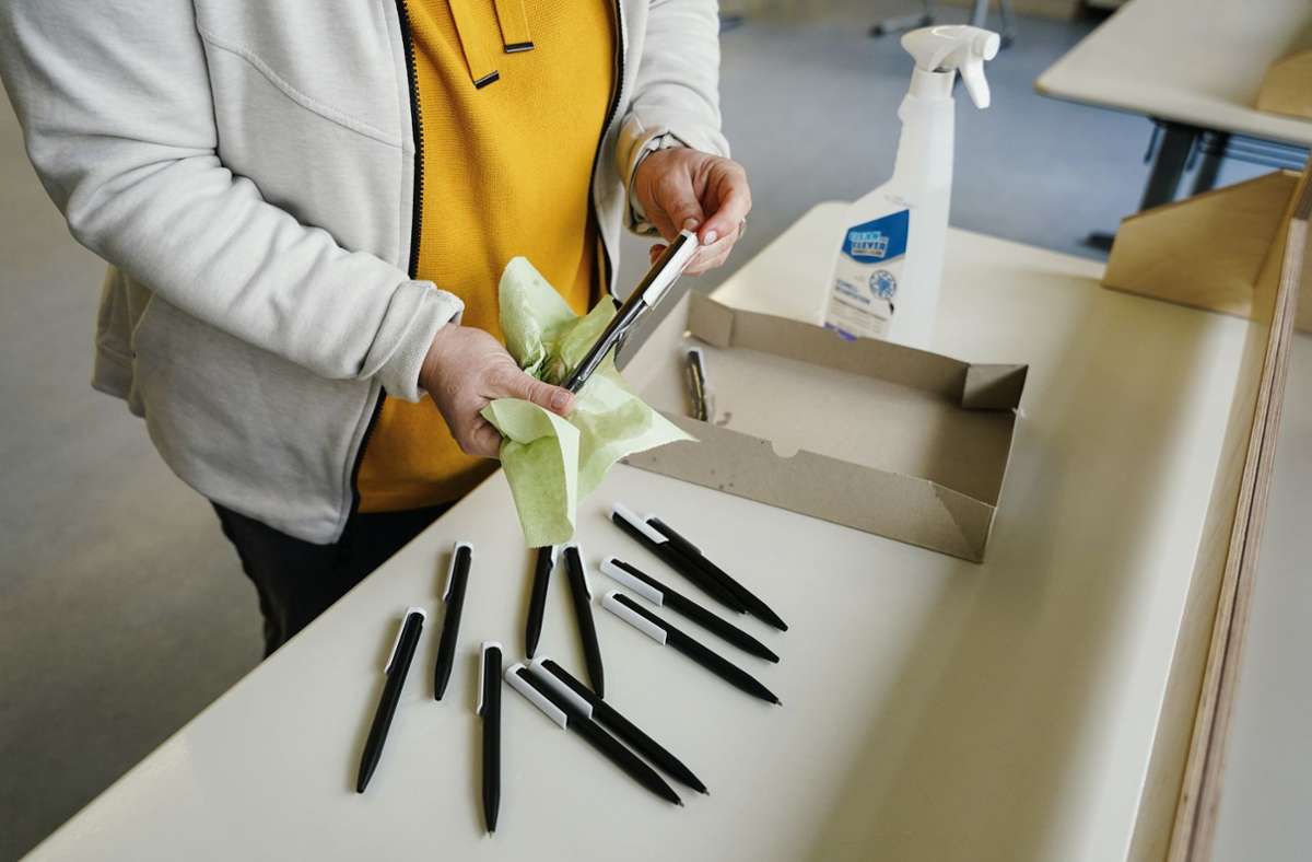 Die Wahl im Zeichen von Corona: Ein Wahlhelferin desinfiziert in einem Mannheimer Wahllokal Kugelschreiber, ...