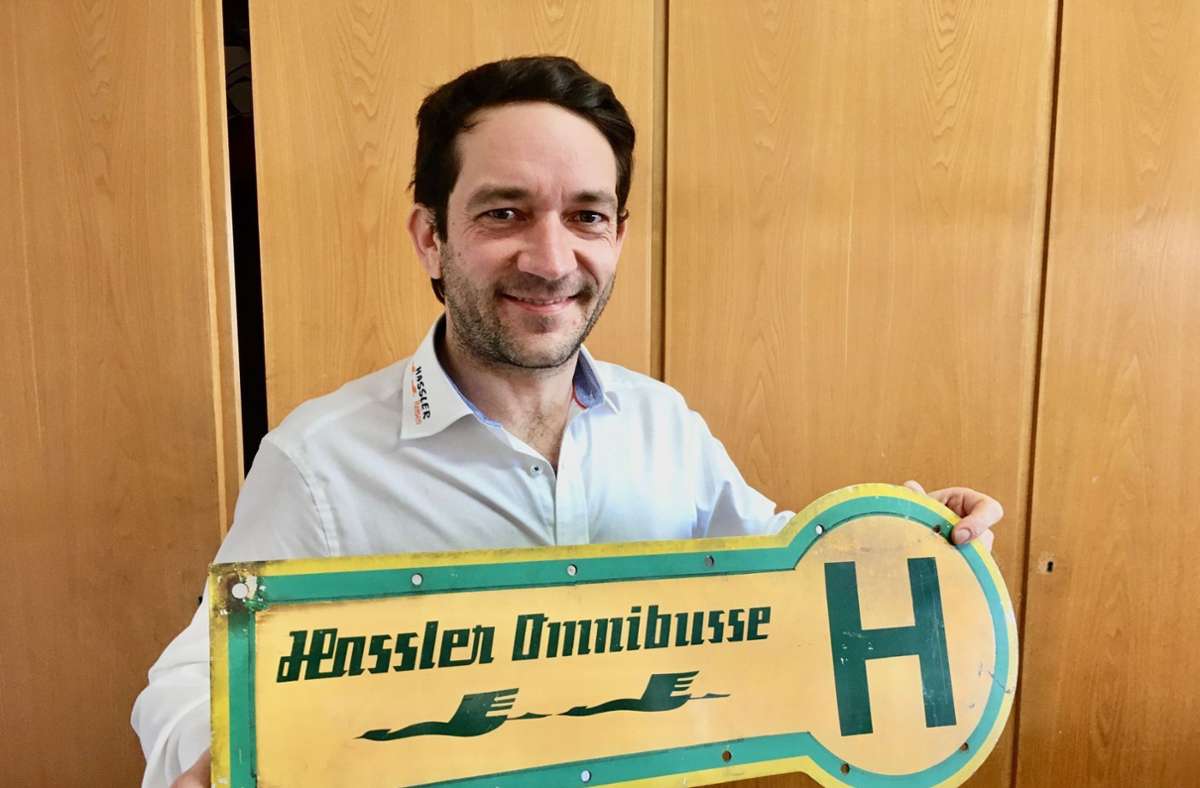 Firmenchef Dominik Hassler mit einem alten Bushaltestellen-Schild.