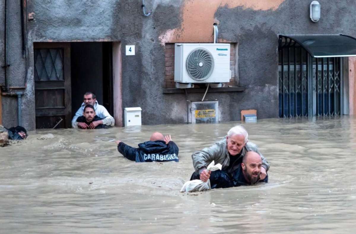 Carabinieri tragen Anwohner huckepack durch die überschwemmten Straßen.