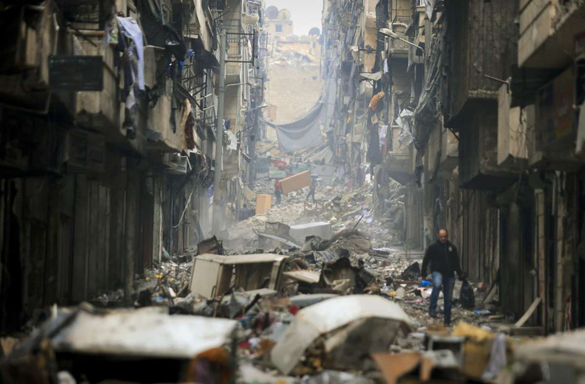 Menschen ziehen im Jahr 2017 durch die Ruinen Aleppos.