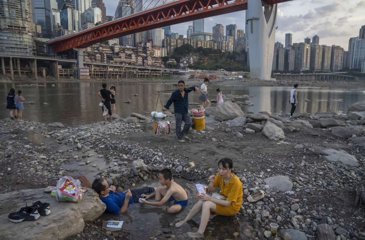 Chongqing: Menschen sitzen in einem flachen Wasserbecken im Flussbett des Jialing-Flusses, eines Nebenflusses des Jangtse.