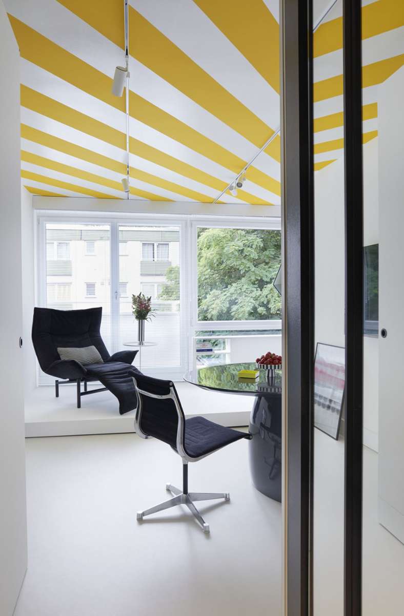 Der gelb-weiße Deckenanstrich macht das kleine Apartment  hell und cool – als säße man unter einer Markise im Freien.