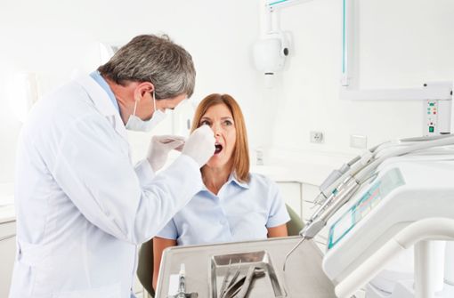 Ein Zahnarzt setzt die Implantate ein. Foto: Adobe Stock/Robert Kneschke