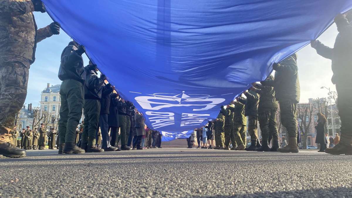 Ein riesige blaue Fahne mit der Aufschrift Latvija Nato 20 wird vor dem Freiheitsdenkmal entrollt. Lettland feiert 20 Jahre Nato-Mitgliedschaft.
